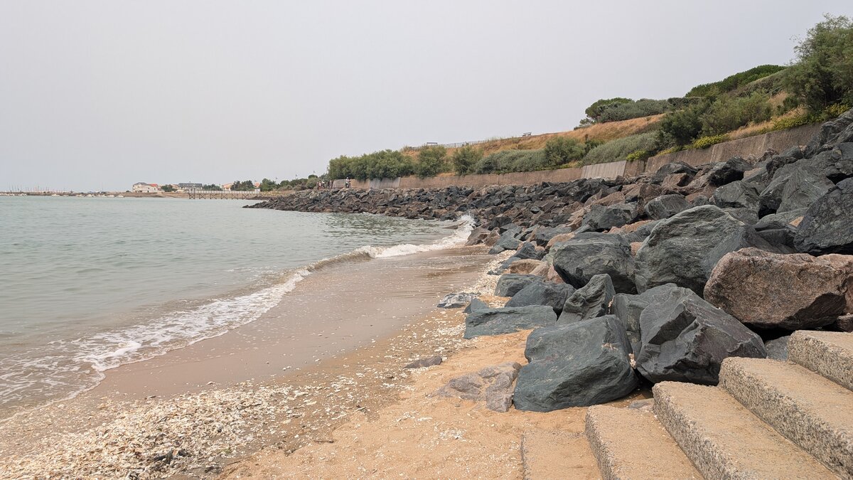 Plage de galets sur la côte atlantique en Bretagne, escalier descendant vers l'océan